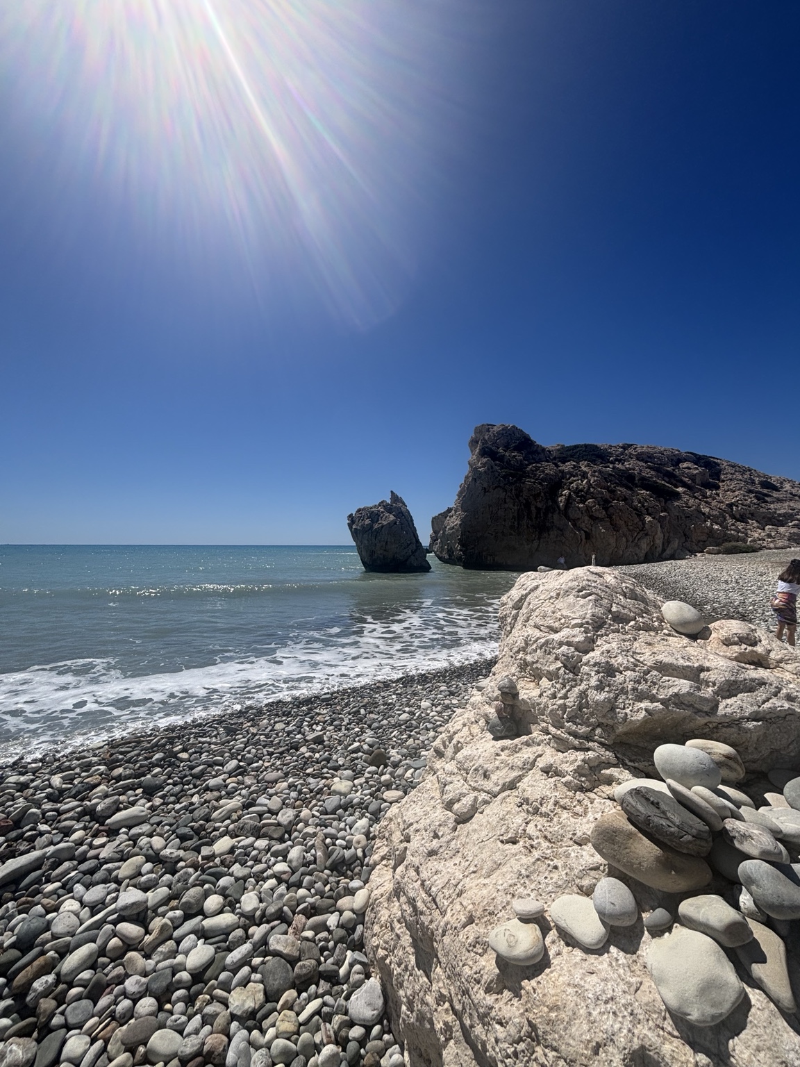 Dunkler Kieselstrand und Brandung bei Petra tou Romiou